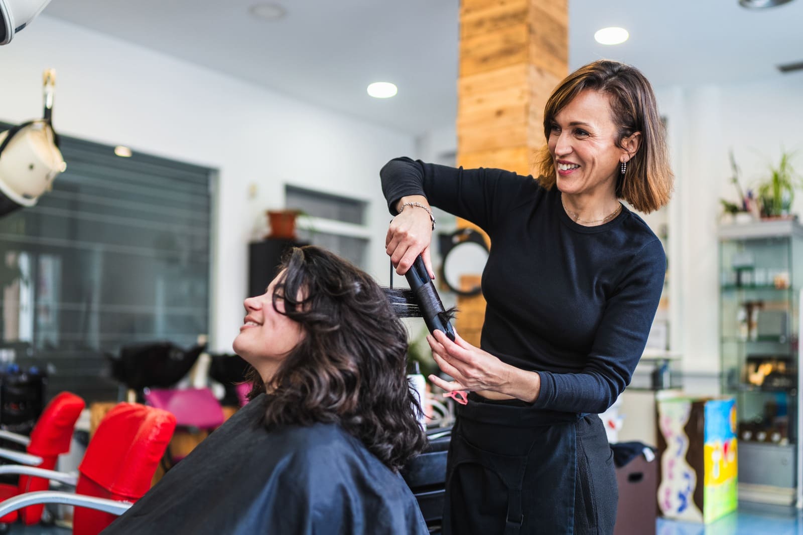 Frizerka radi frizuru klijentici u salonu